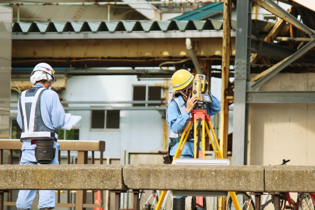 ノートパソコンのあるデスクで、笑顔のビジネスマンがペンを持ち、会議または面接をしている様子
